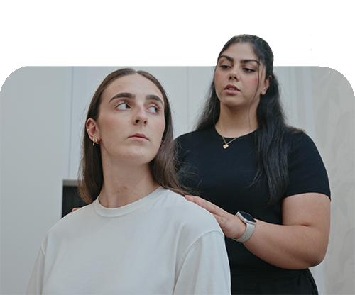 A chiropractor gently places hands on a seated patient’s shoulders while observing neck rotation during a posture and mobility assessment in a clinical setting.