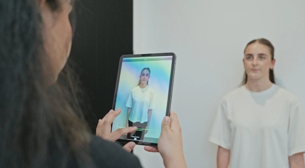 Clinician using a tablet to capture and assess a patient’s standing posture in a clinical setting
