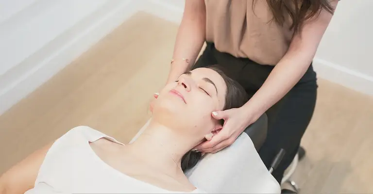 Chiropractor providing gentle neck support during an in-clinic treatment