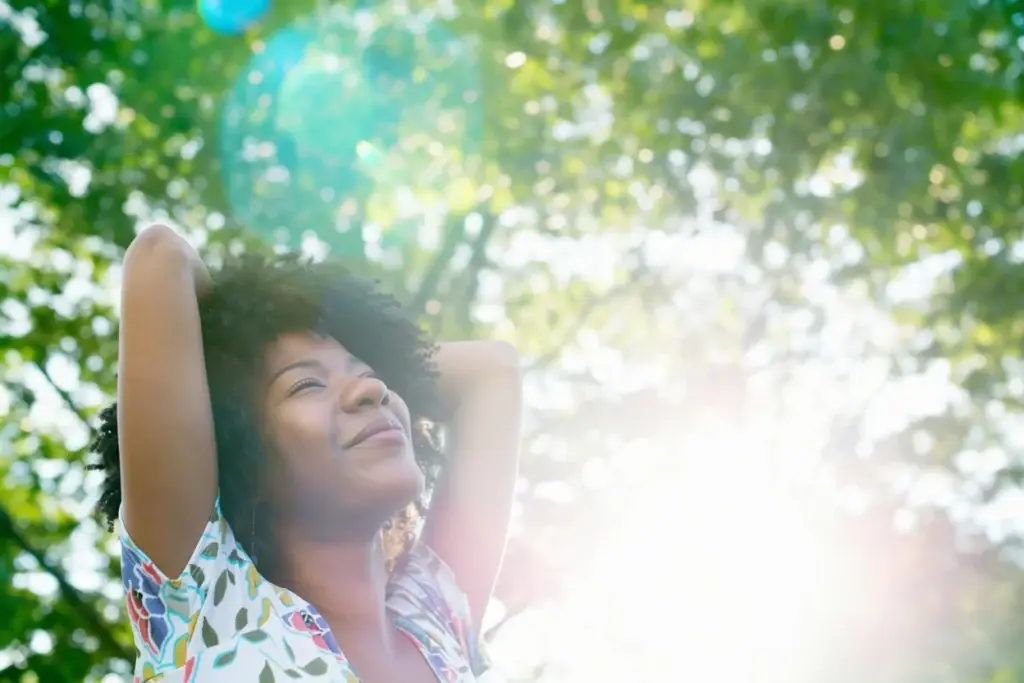 Woman standing outdoors with arms raised, enjoying relaxation and freedom of movement