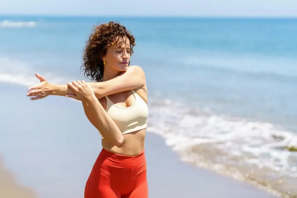Woman stretching her shoulder and upper body on a beach to improve mobility