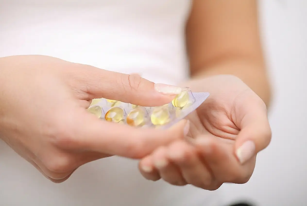 Person holding a blister pack of capsules, representing medication or supplements